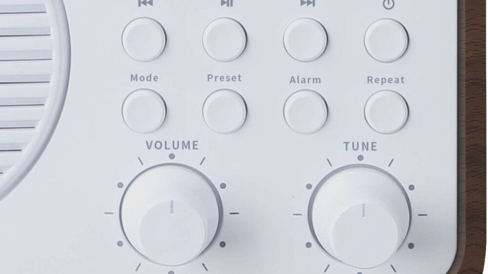 Panel sterowania z przyciskami oznaczonymi jako Mode, Preset, Alarm, Repeat oraz pokrętłami Volume i Tune. Widoczne są również symbole odtwarzania i przewijania.