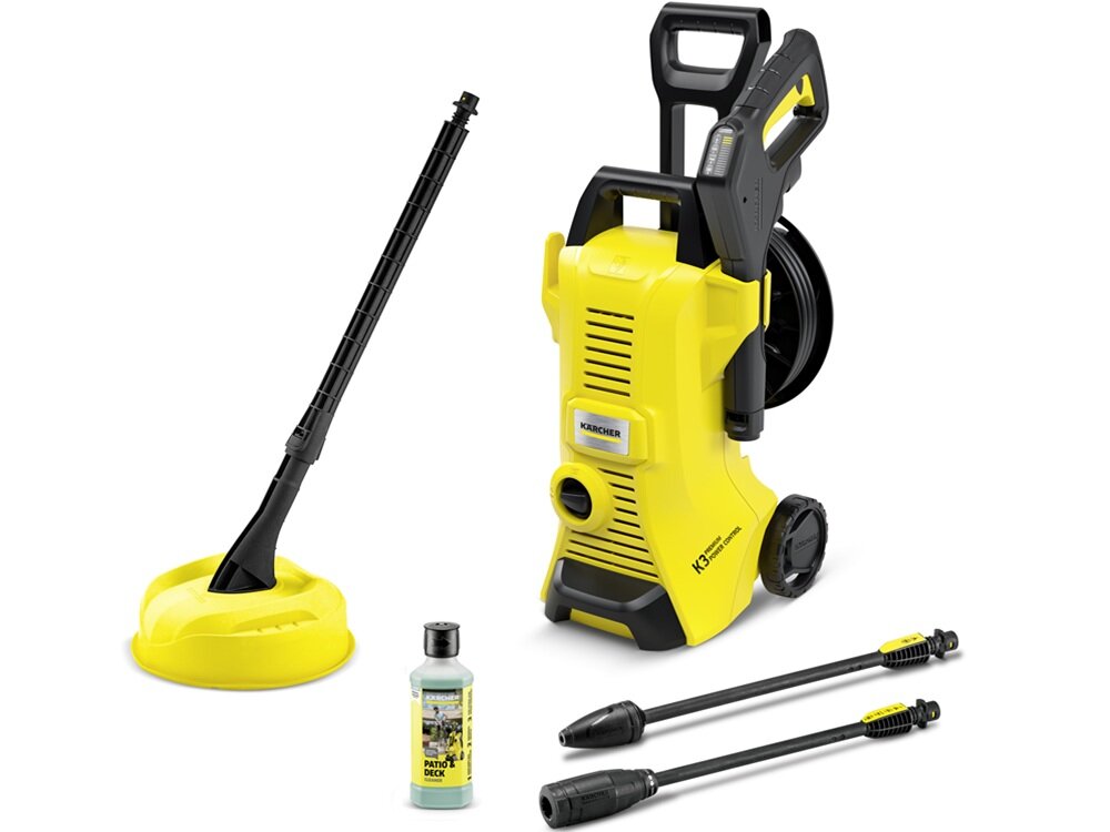 Na obrazie znajduje się żółta myjka ciśnieniowa z logo KARCHER, wyposażona w uchwyt i koła. Obok niej widoczne są akcesoria: dysza, butelka z płynem oraz okrągła szczotka.