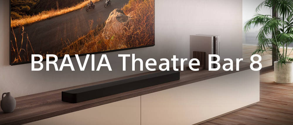 Na obrazie widoczny jest czarny soundbar umieszczony na drewnianej półce pod telewizorem. Na środku obrazu znajduje się tekst: \'BRAVIA Theatre Bar 8\'.