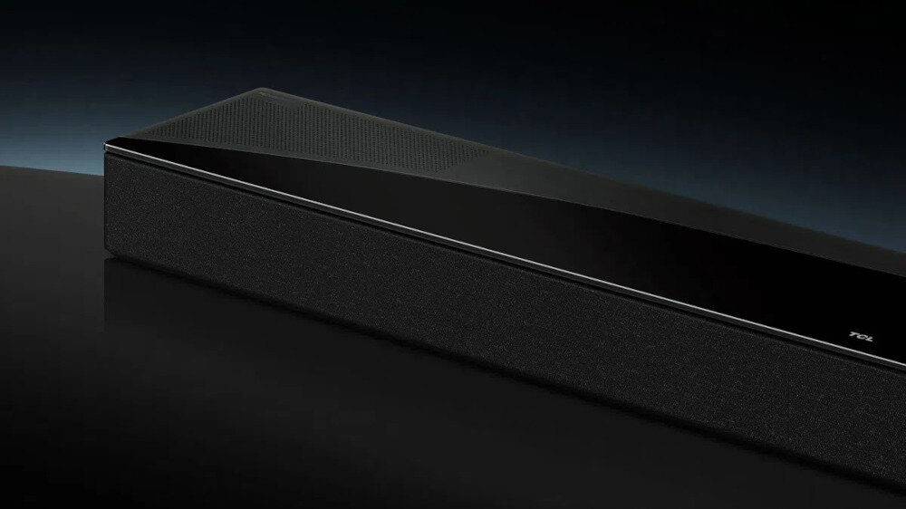 Czarny soundbar z widocznym logo TCL na przednim panelu, umieszczony na ciemnym tle.