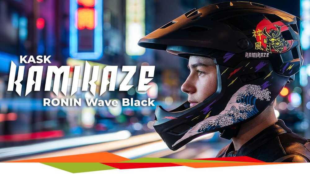 Osoba nosi czarny kask z grafiką fali i samuraja, na tle rozmytego miejskiego krajobrazu nocą. Widoczny tekst: \'KASK KAMIKAZE RONIN Wave Black\'.