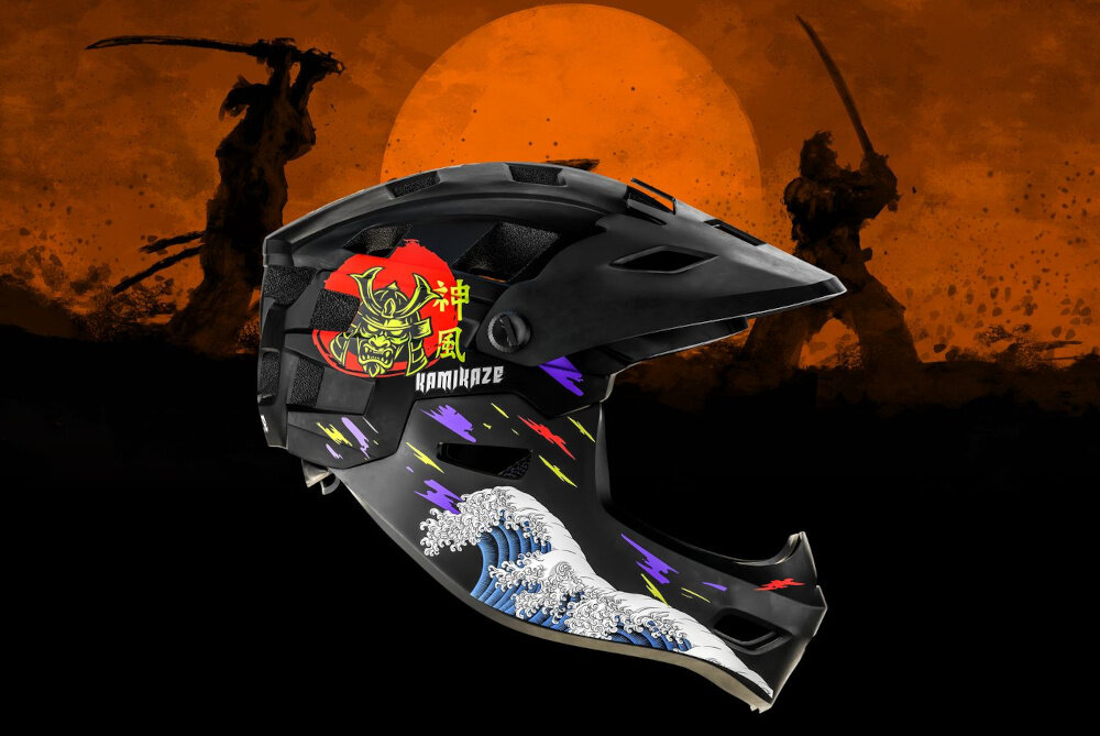 Czarny kask full face z kolorowymi wzorami, w tym falami i samurajem, oraz napisem \'KAMIKAZE\'. W tle widoczne są sylwetki samurajów na pomarańczowym tle.