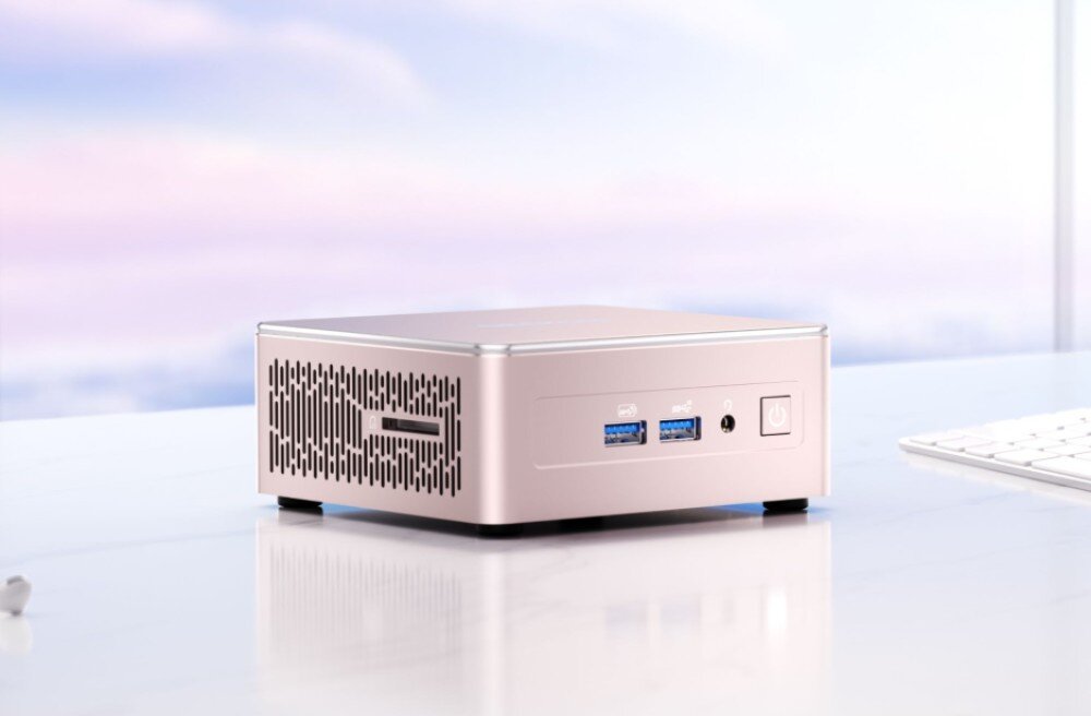 Komputer GEEKOM A5 Kompaktowy komputer stacjonarny stojący na jasnym biurku, widoczny przedni panel z portami USB, gniazdem audio i włącznikiem oraz boczna kratka wentylacyjna