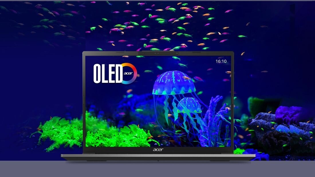 Laptop z wyświetlaczem pokazującym kolorowy obraz meduz i ryb na tle ciemnego oceanu. Na ekranie widoczny jest napis \'OLED acer\' oraz godzina 16:10.
