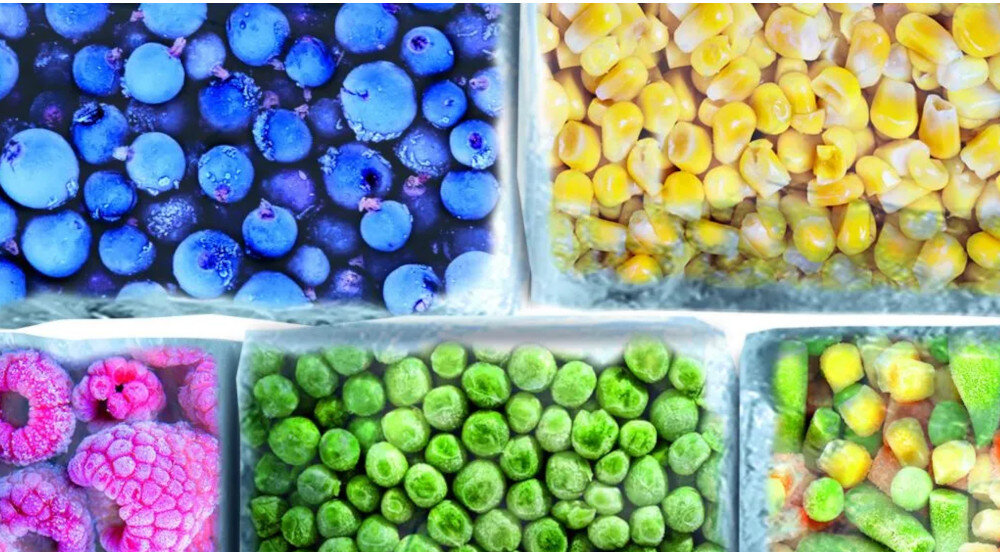 KUCHENKA MIKROFALOWA GORENJE MO20A4XH Zbliżenie na zamrożone produkty w oddzielnych przegródkach, w tym jagody, kukurydzę, maliny i groszek. Na powierzchni widać warstwę lodu, co podkreśla proces mrożenia i długotrwałego przechowywania żywności rozmrażanie mikrofalowe równomierne rozmrażanie szybkie rozmrażanie żywność