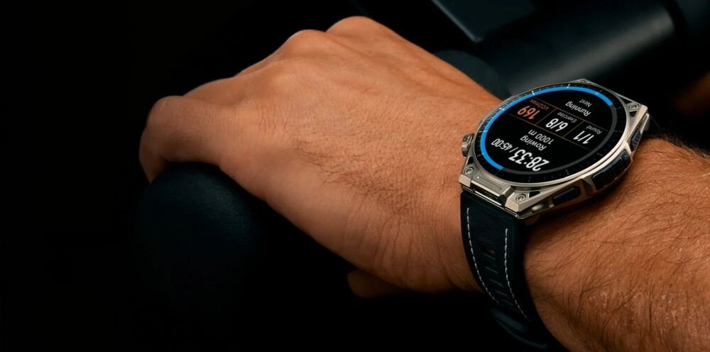 Na zdjęciu widoczny jest smartwatch na nadgarstku osoby, z wyświetlaczem pokazującym dane dotyczące tętna i czasu. Pasek zegarka jest ciemny, a koperta ma metaliczny wygląd.