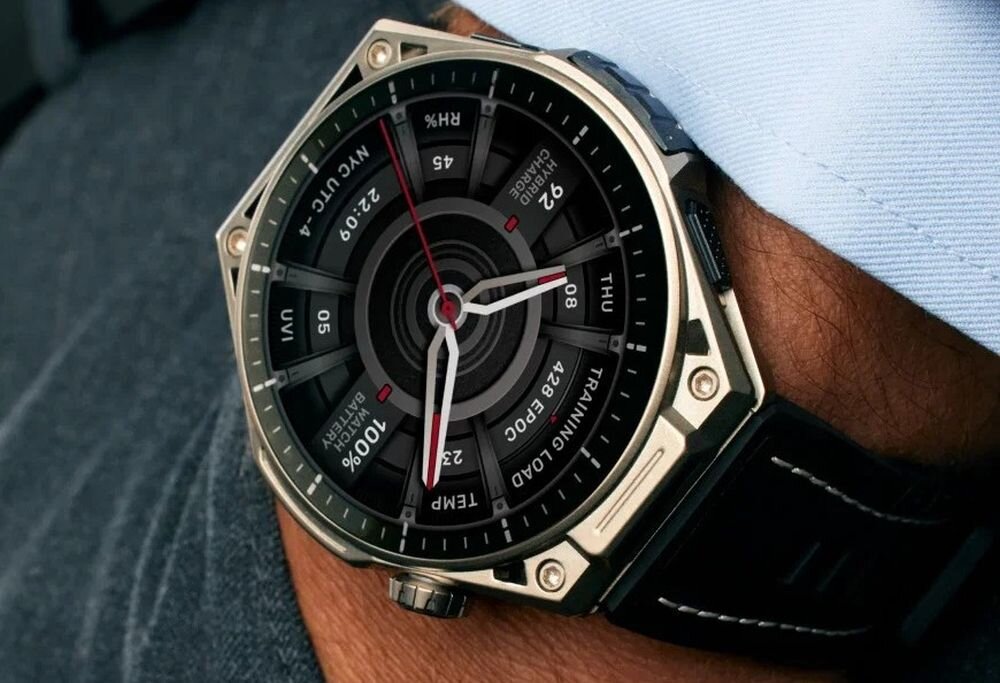 Na zdjęciu widoczny jest smartwatch z okrągłą tarczą, na której znajdują się wskazówki oraz różne wskaźniki i napisy, takie jak \'NVC UTC+4\', \'22:09\', \'92\', \'THU\', \'TRAINING LOAD\'.