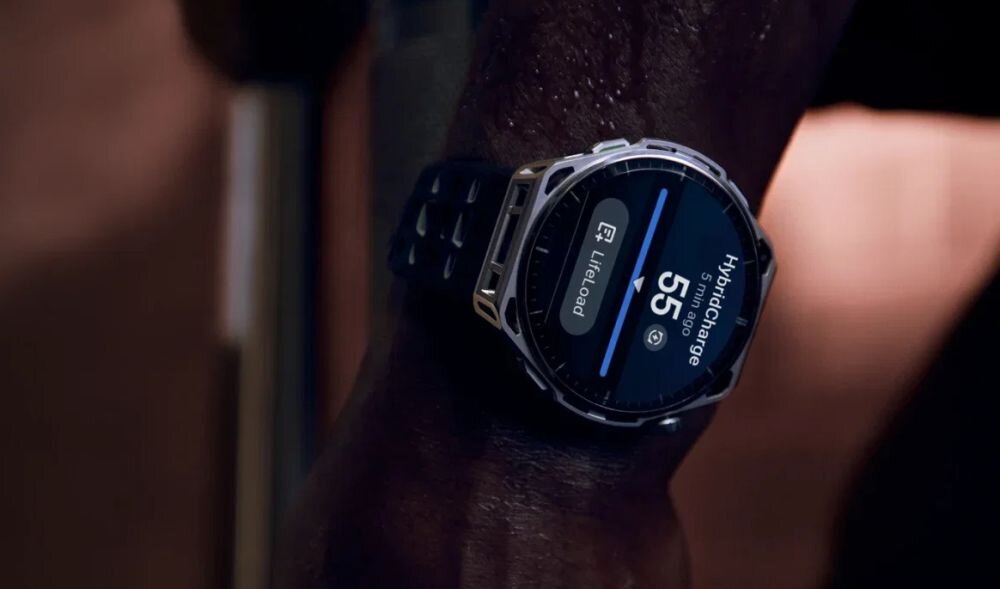 Na zdjęciu widoczny jest smartwatch z okrągłym wyświetlaczem, na którym znajduje się tekst: \'Hybridcharge 55\'.