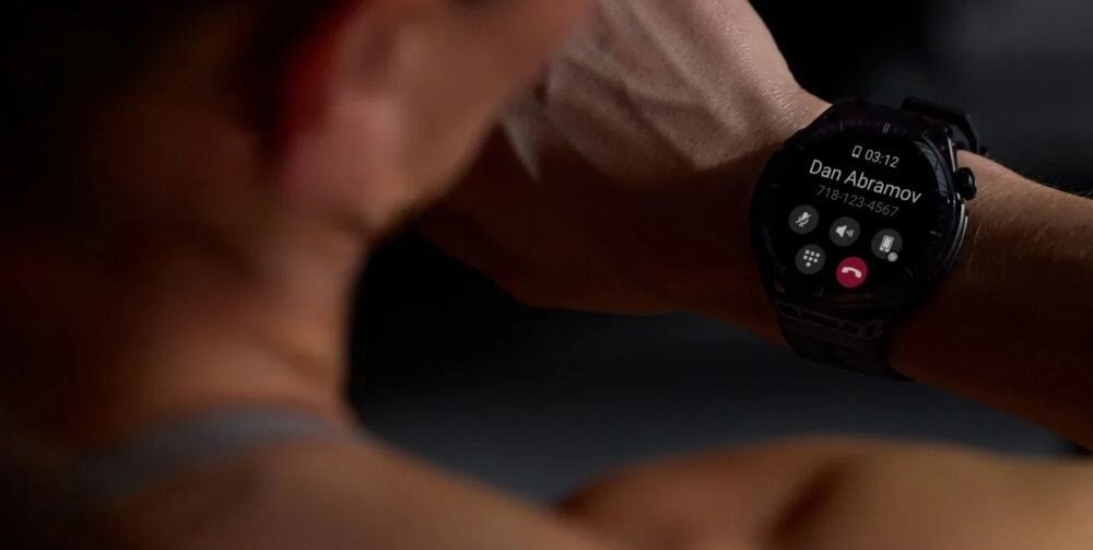 Osoba patrzy na smartwatch, na którego ekranie wyświetla się połączenie przychodzące od \'Dan Abramov\' z numerem \'718-123-4567\'.