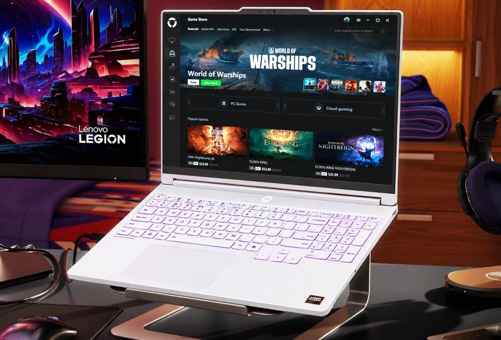 Na obrazie widoczny jest laptop z otwartym ekranem, na którym wyświetlana jest aplikacja z grami, w tym \'World of Warships\'. Obok laptopa znajduje się monitor z logo \'Lenovo Legion\'.