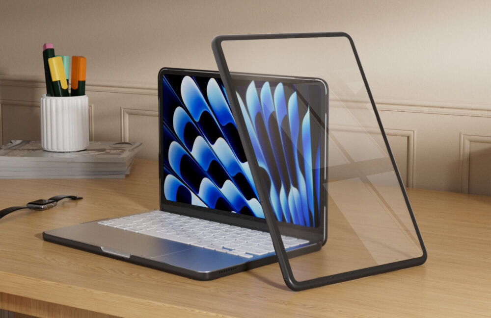 Na drewnianym biurku stoi otwarty laptop z wyświetlaczem pokazującym abstrakcyjny wzór w niebieskich odcieniach. Obok laptopa znajduje się przezroczyste etui z czarną ramką.