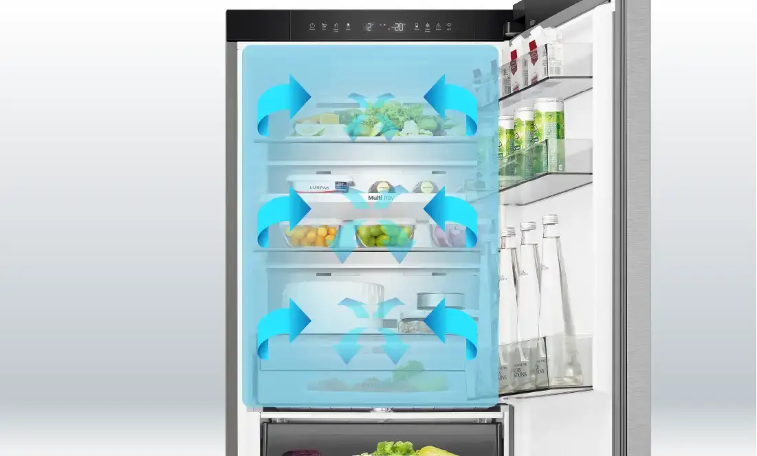 Wnętrze lodówki z otwartymi drzwiami, na półkach znajdują się różne produkty spożywcze. Widoczne są niebieskie strzałki wskazujące na cyrkulację powietrza wewnątrz lodówki.