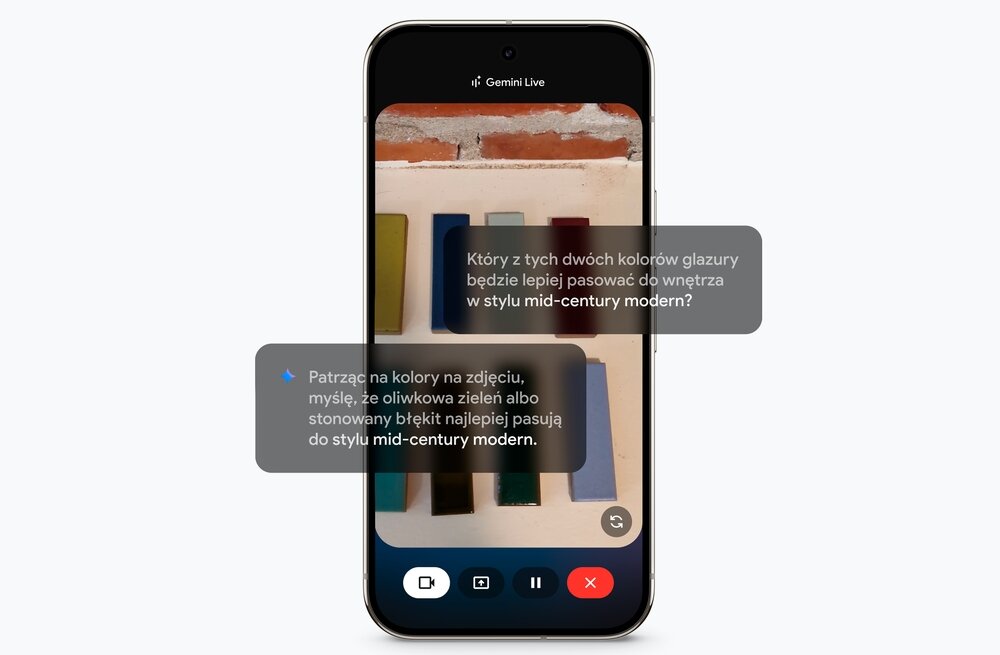 Smartfon wyświetla aplikację z rozmową tekstową na tle zdjęcia kolorowych płytek. Tekst na ekranie: \'Który z tych dwóch kolorów glazury będzie lepiej pasować do wnętrza w stylu mid-century modern?\' oraz \'Patrząc na kolory na zdjęciu, myślę, że oliwkowa zieleń albo stonowany błękit najlepiej pasują do stylu mid-century modern.\'