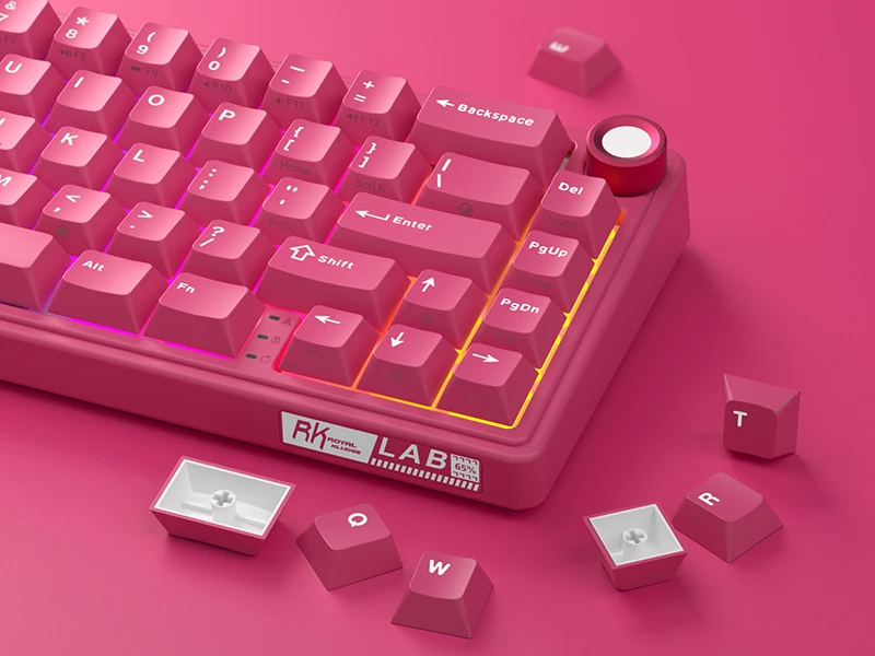 Różowa klawiatura mechaniczna z widocznymi klawiszami, takimi jak \'Enter\', \'Shift\', \'Backspace\', oraz logo \'RK Royal Kludge LAB\'. Obok klawiatury leżą zdjęte klawisze \'Q\', \'W\', \'R\', \'T\'.