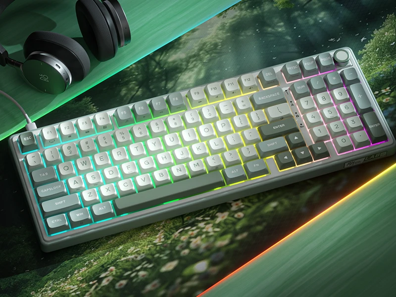 Na obrazie znajduje się klawiatura z podświetleniem RGB, umieszczona na podkładce z motywem natury. Obok klawiatury leżą słuchawki z widocznym logo producenta.