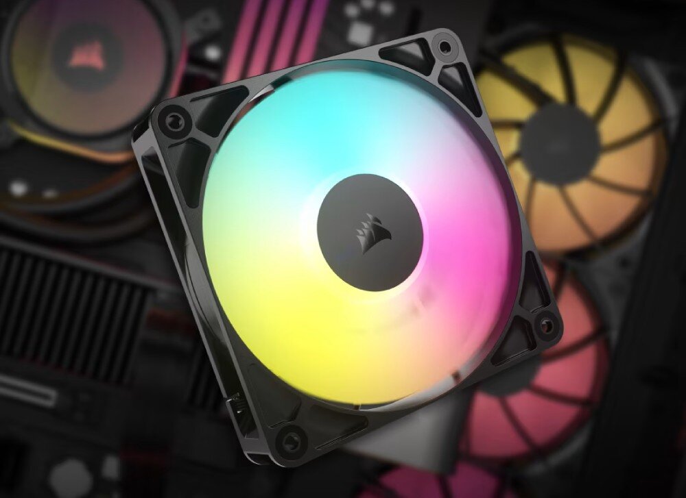 Obraz przedstawia wentylator komputerowy z podświetleniem RGB, z widocznym logo producenta na środku. W tle znajdują się inne elementy komputerowe, w tym wentylatory z różnokolorowym podświetleniem.