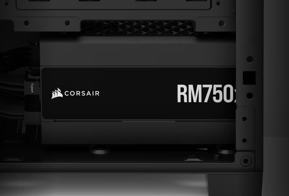 Obraz przedstawia wnętrze komputera z widocznym zasilaczem oznaczonym logo \'CORSAIR\' i napisem \'RM750x\'.