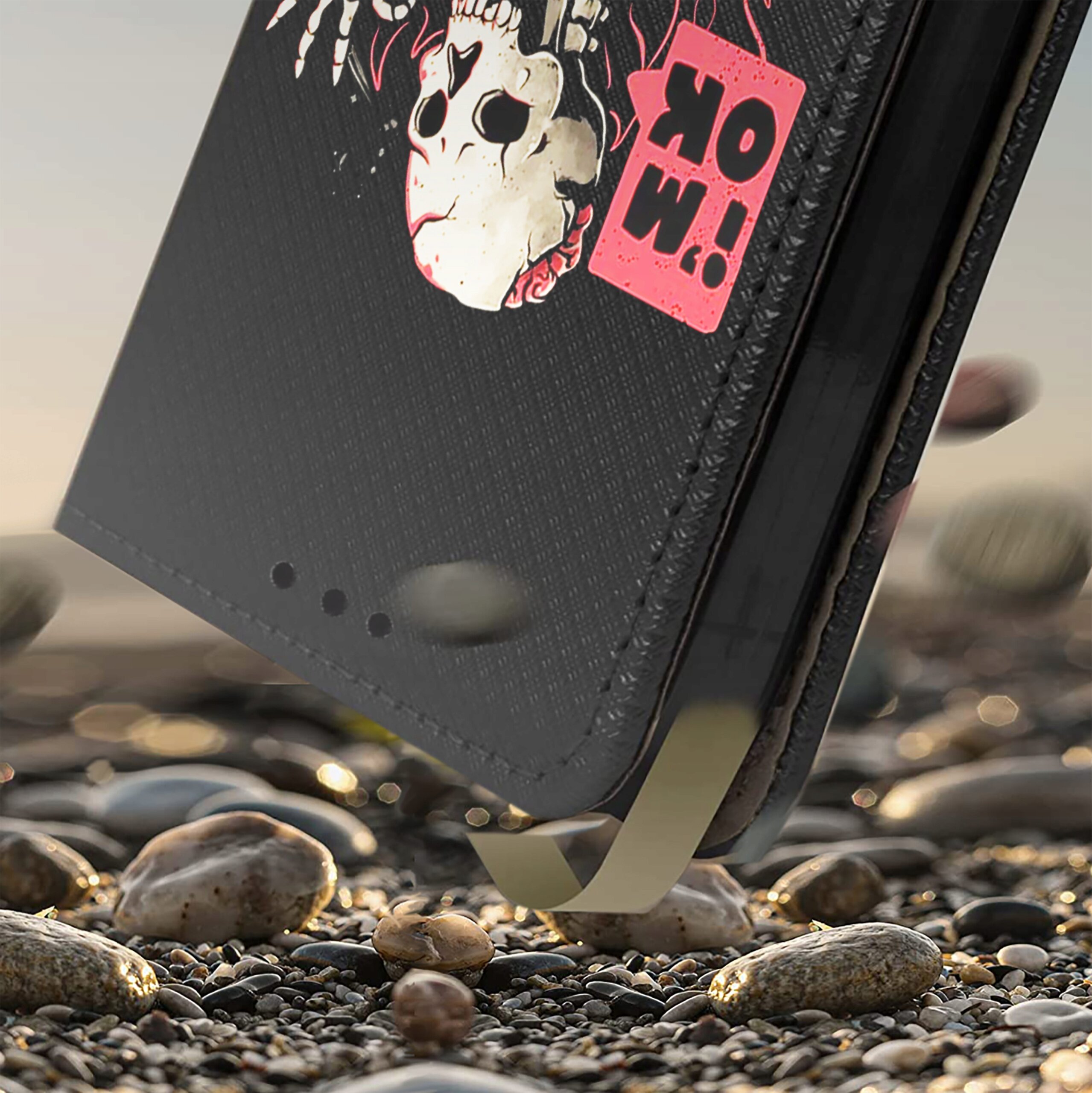 Etui do telefonu z grafiką czaszki i napisem \'WOW!\' na tle kamieni. Etui ma ciemny kolor z wyraźnym wzorem i otworami na dole.