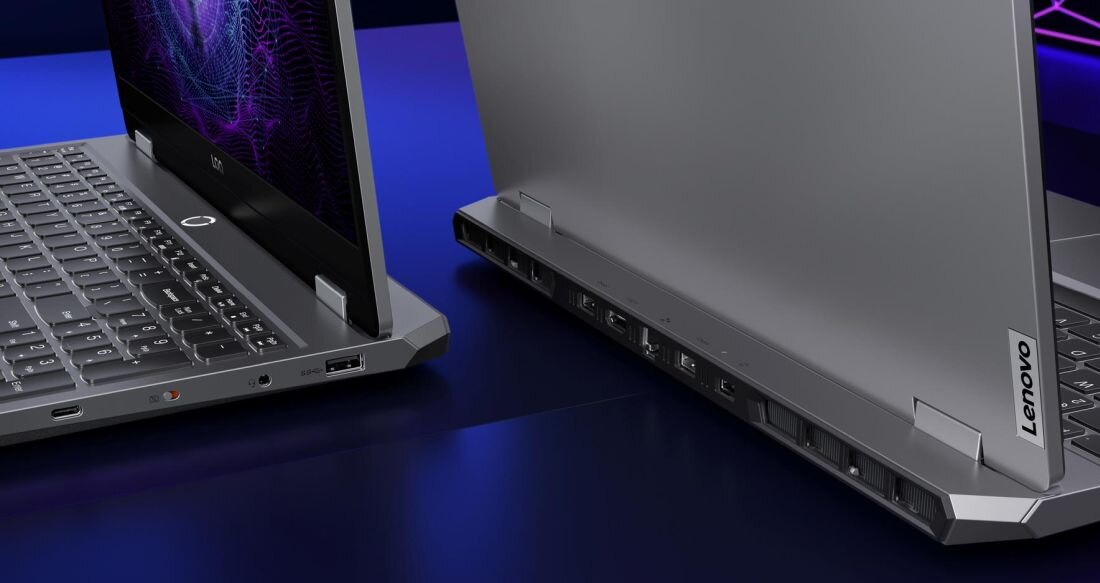 Dwa laptopy z otwartymi pokrywami, widoczne klawiatury i porty z tyłu. Na jednym z laptopów widoczne jest logo \'Lenovo\'.