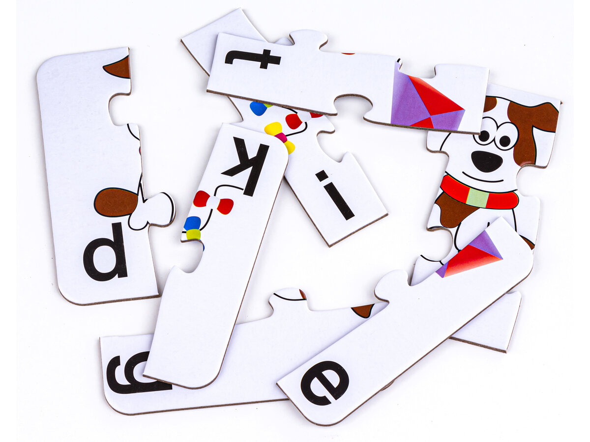 Na obrazie widoczne są elementy puzzli z literami i fragmentami obrazków, w tym pies i kolorowy latawiec. Litery na puzzlach to \'d\', \'k\', \'i\', \'e\'.
