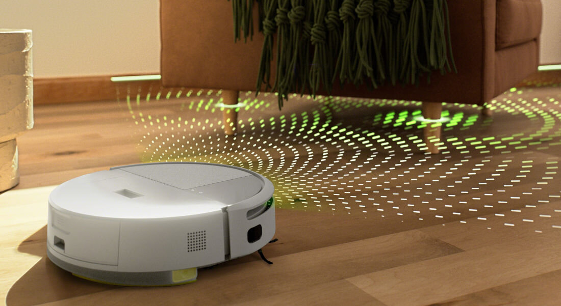 Na drewnianej podłodze znajduje się biały robot sprzątający, emitujący zielone i białe linie świetlne w kierunku pobliskiej kanapy. W tle widoczna jest część pomieszczenia z brązową kanapą i zielonym kocem.