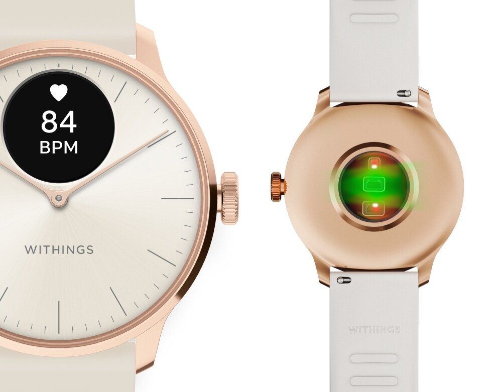Na obrazie widoczny jest smartwatch w kolorze różowo-złotym z wyświetlaczem pokazującym 84 BPM oraz logo \'WITHINGS\'. Obok znajduje się tylna część zegarka z zielonym światłem czujnika.