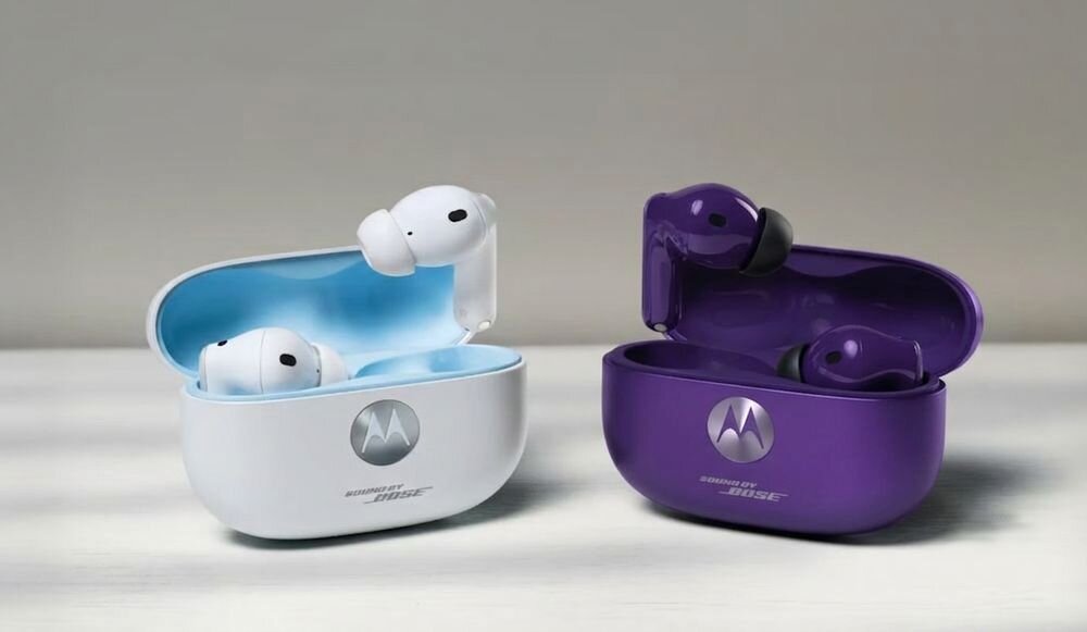 Na obrazie widoczne są dwa etui z bezprzewodowymi słuchawkami dokanałowymi, jedno białe z niebieskim wnętrzem, drugie fioletowe. Na obu etui znajduje się logo Motorola oraz napis \'Sound by Bose\'.