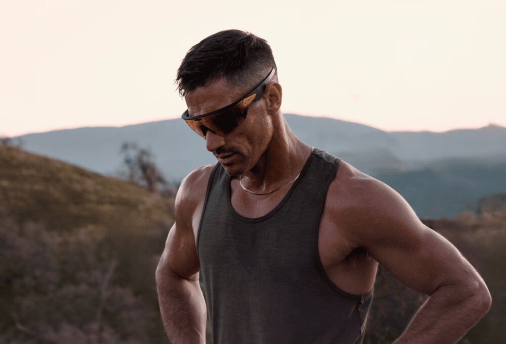 Okulary META Oakley Vanguad Mężczyzna z brodą w ciemnej koszulce i okularach przeciwsłonecznych trzyma kij golfowy na tle zielonej trawy, opis