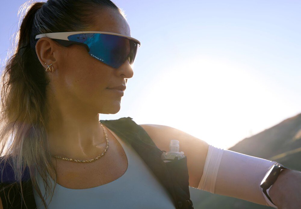 Okulary META Oakley Vanguad Mężczyzna z brodą w ciemnej koszulce i okularach przeciwsłonecznych trzyma kij golfowy na tle zielonej trawy, opis