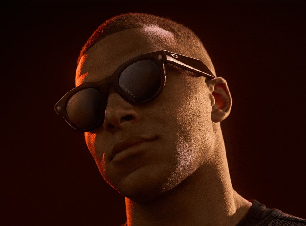 Okulary META Oakley HSTN Mężczyzna z profilu w okularach przeciwsłonecznych, oświetlony ciepłym, pomarańczowym światłem konturowym na ciemnym tle, opis