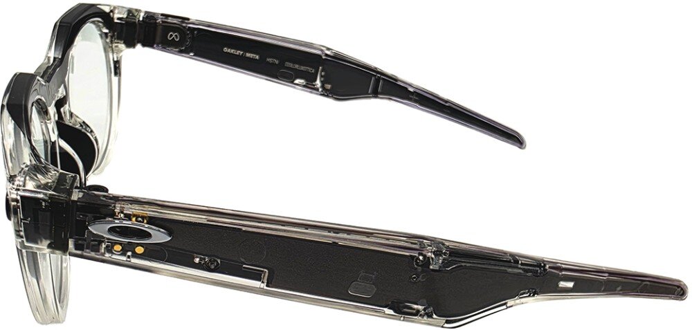 Przezroczyste okulary z widocznymi elementami elektronicznymi w zausznikach. Na zauszniku znajduje się logo Oakley oraz napisy: \'OAKLEY META HSTN OO9464-0152\'.