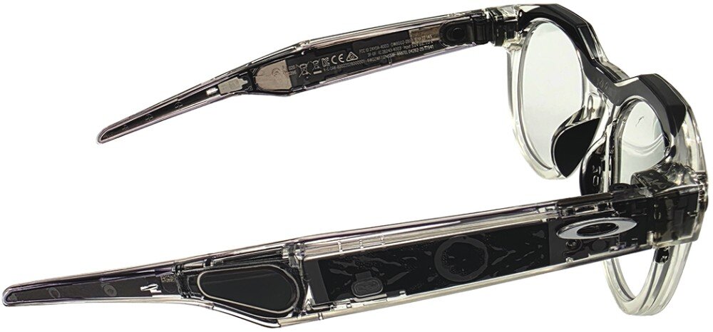 Przezroczyste okulary z widocznymi elementami elektronicznymi w zausznikach oraz logo Oakley na jednym z nich.