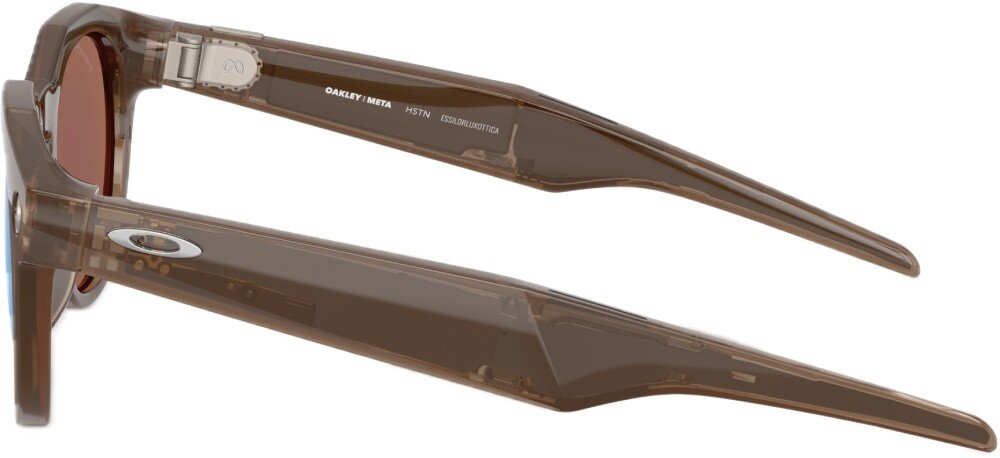 Brązowe okulary przeciwsłoneczne z przezroczystymi oprawkami i ciemnymi soczewkami. Na zauszniku widoczny jest napis: \'OAKLEY META HSTN OO9464-0153\'.