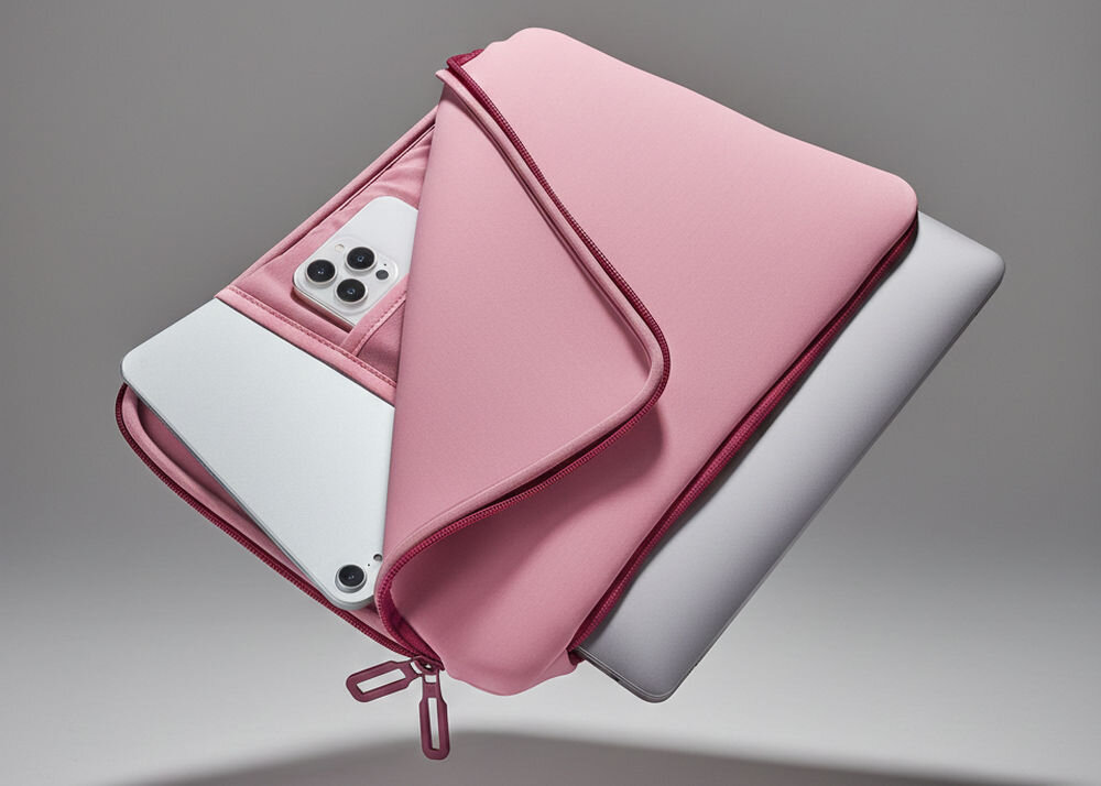 Różowe etui na laptopa z zamkiem błyskawicznym, w którym znajduje się srebrny laptop i smartfon z trzema obiektywami aparatu.