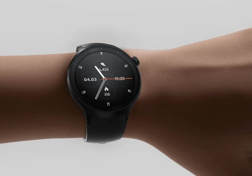Na zdjęciu widoczny jest czarny smartwatch na nadgarstku, z okrągłym wyświetlaczem pokazującym datę 04.03, godzinę 11:35 oraz liczbę kroków 425 i spalone kalorie 318.