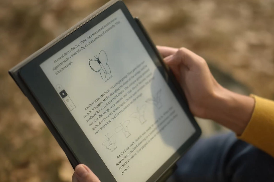 Osoba trzyma czytnik e-booków, na którym wyświetlany jest tekst z ilustracjami motyla i diagramami. Ekran jest czytelny, a urządzenie ma ciemną obudowę.