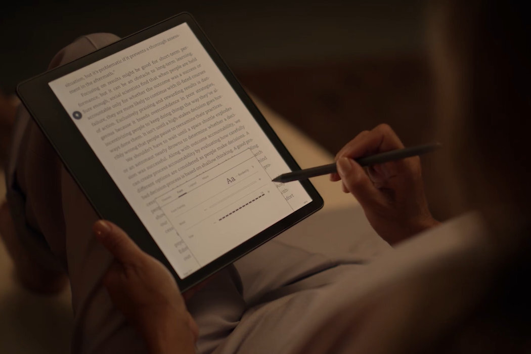 Osoba trzyma czytnik e-booków z wyświetlonym tekstem i menu ustawień czcionki, używając rysika do interakcji z ekranem.