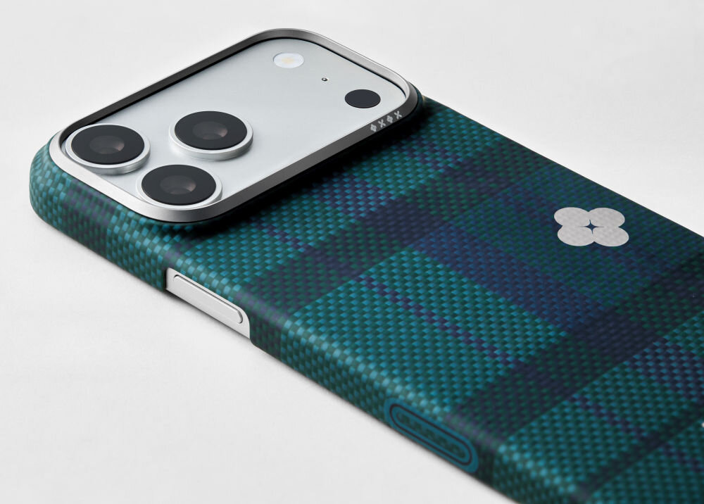 Etui na telefon z wzorem w kratę w odcieniach zieleni i niebieskiego, z widocznymi trzema obiektywami aparatu. Na etui znajduje się mały, biały symbol przypominający kwiat.