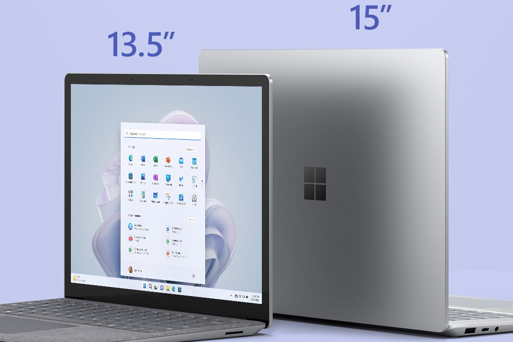 Na obrazie widoczne są dwa laptopy z logo w kształcie czterech kwadratów. Na ekranie jednego z nich wyświetlony jest pulpit systemu Windows z ikonami aplikacji, a nad nimi widnieją napisy \'13.5\
