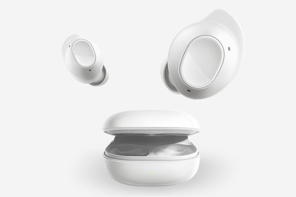 Galaxy Buds FE Na obrazie widoczne są białe bezprzewodowe słuchawki douszne oraz otwarte etui ładujące. Etui ma zieloną diodę sygnalizacyjną na przedniej stronie.
