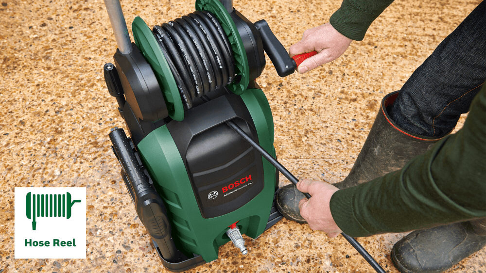 Osoba obsługuje zieloną myjkę ciśnieniową z logo BOSCH, z nawiniętym wężem na bębnie. Obok znajduje się ikona z napisem \'Hose Reel\'.