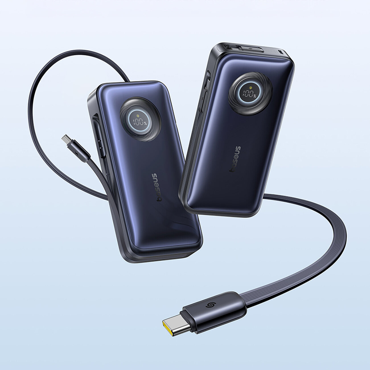 Na obrazie widoczne są dwa powerbanki z logo \'Baseus\', każdy z wyświetlaczem pokazującym stan naładowania. Obok znajduje się zwinięty kabel USB-C.