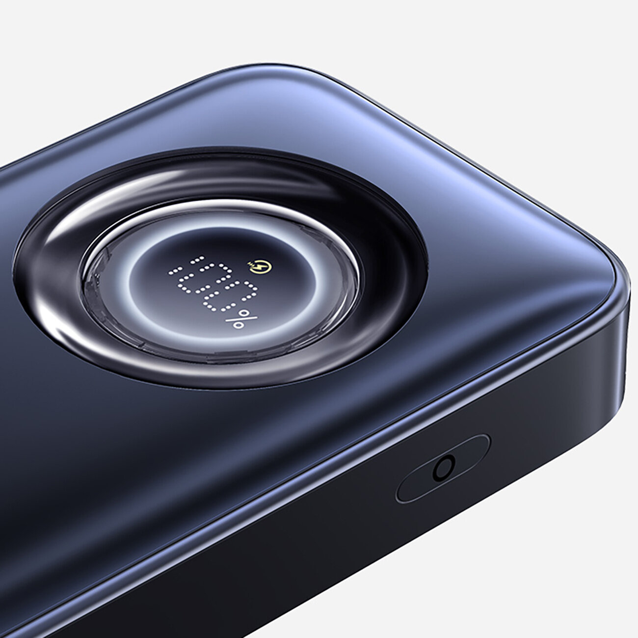 Na obrazie widoczny jest ciemny powerbank z okrągłym wyświetlaczem pokazującym \'100%\'. Obudowa ma gładką powierzchnię i zaokrąglone krawędzie.