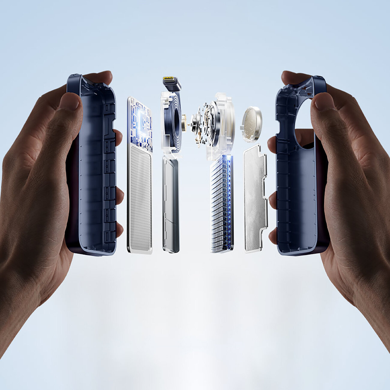 Obraz przedstawia rozłożony na części powerbank, trzymany przez dwie dłonie. Widać różne komponenty wewnętrzne, takie jak obudowa, płytki elektroniczne i złącza.