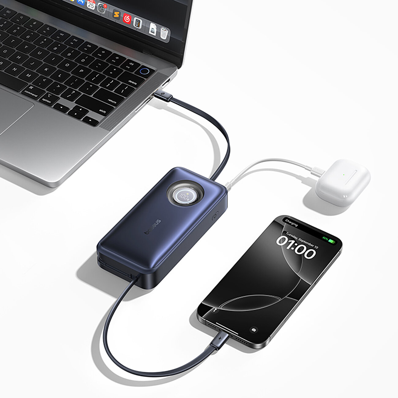 Na obrazie widać powerbank podłączony do laptopa, smartfona i słuchawek bezprzewodowych. Na ekranie smartfona widoczny jest napis \'Charging\' oraz godzina \'01:00\'.