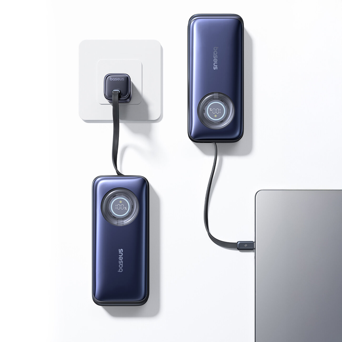 Na obrazie widoczne są dwa powerbanki w kolorze ciemnoniebieskim, podłączone do gniazdka i laptopa. Na wyświetlaczu jednego z nich widnieje napis \'100%\'.