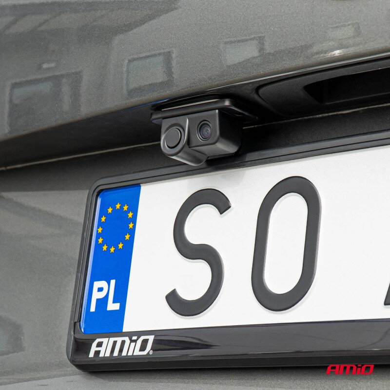 Na obrazie widoczna jest kamera cofania zamontowana nad tablicą rejestracyjną samochodu. Tablica rejestracyjna ma oznaczenie \'PL\' oraz logo \'AMiO\'.