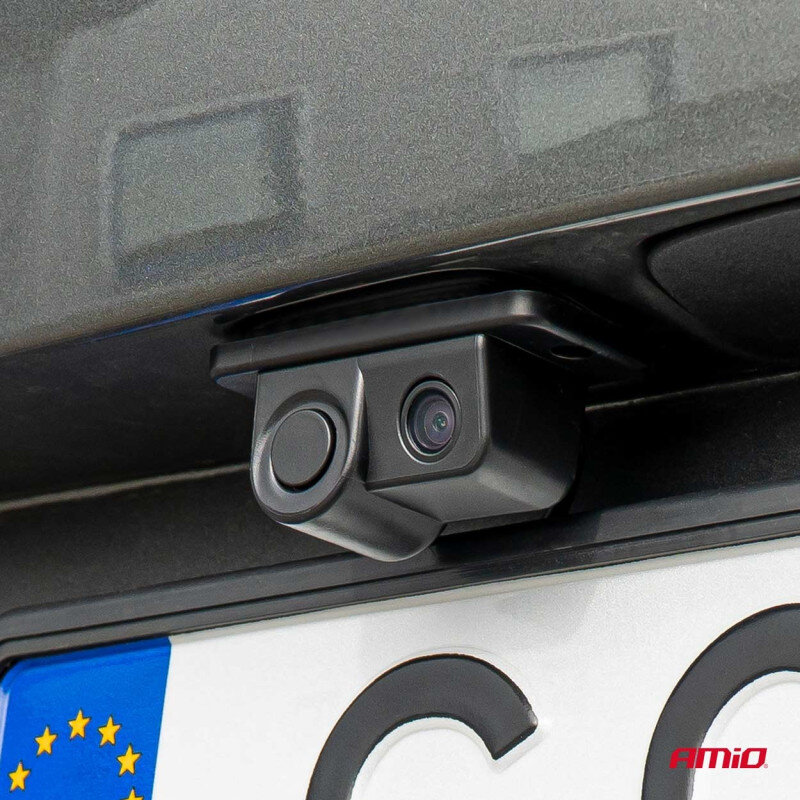 Na obrazie widoczna jest kamera cofania zamontowana nad tablicą rejestracyjną pojazdu. W prawym dolnym rogu znajduje się logo \'AMiO\'.