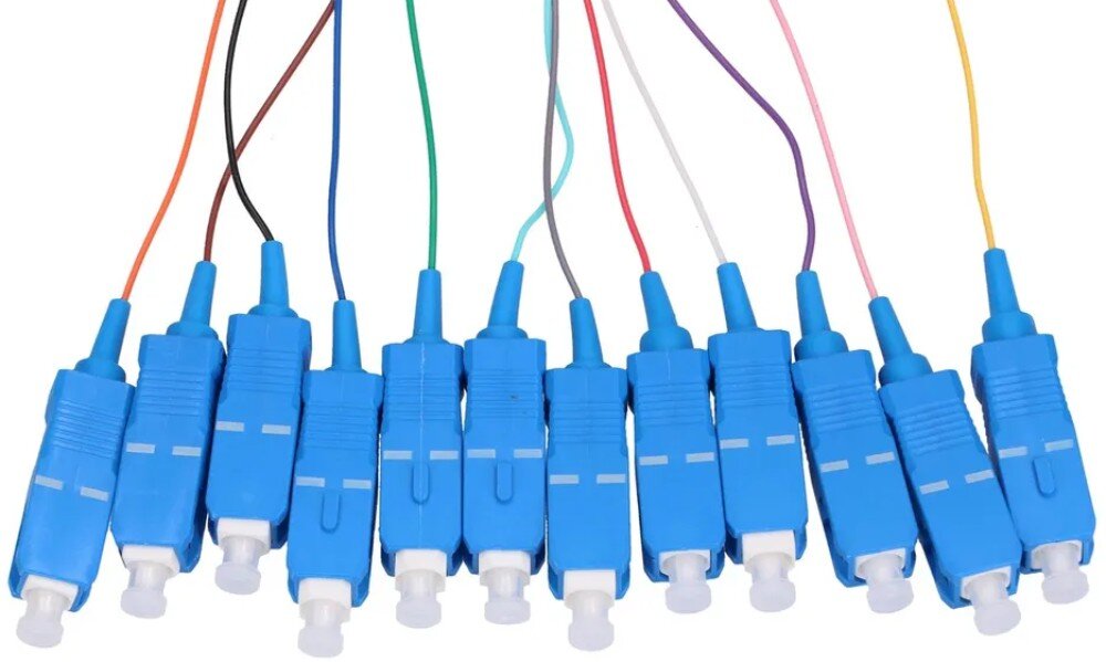 Kabel Pigtail - SC/UPC EXTRALINK EX.0356 Rząd niebieskich wtyków światłowodowych z białymi nasadkami ochronnymi połączonych z przewodami w różnych kolorach