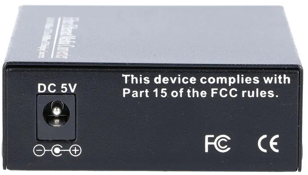 Konwerter światłowodowy EXTRALINK EX.3296 Tylny panel urządzenia z gniazdem zasilania stałego opisanym jako 'DC 5V' po lewej stronie oraz białym napisem 'This device complies with Part 15 of the FCC rules.' i symbolami certyfikacji po prawej stronie